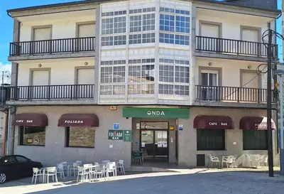 a building with tables and chairs in front of it at Pensión Río Cenza in Villarino de Conso