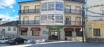 a building with a dog sitting on a balcony at Pensión Río Cenza in Villarino de Conso