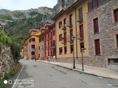 two people walking down a street next to buildings at Ceraca in Pola de Somiedo