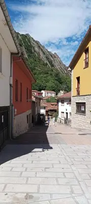 a street with buildings and a mountain in the background at Ceraca in Pola de Somiedo