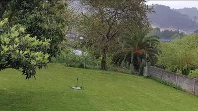 a grassy field with a fence and trees and a river at Chalet en Miño con vistas al mar in Miño