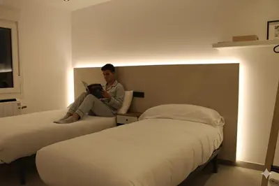 a man sitting on a bed reading a book at Apartamentos Camino Inglés II in Ordes