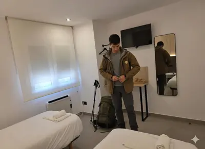 a man standing in a room with a suitcase and a mirror at Apartamentos Camino Inglés II in Ordes