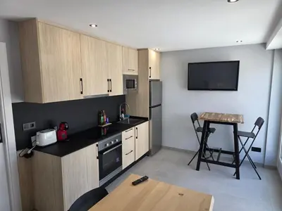 a kitchen with wooden cabinets and a table and a television at Apartamentos Camino Inglés II in Ordes