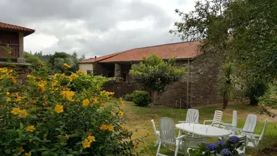 a table and chairs in a garden with flowers at A Pena de Augasantas in Oca de Abaixo