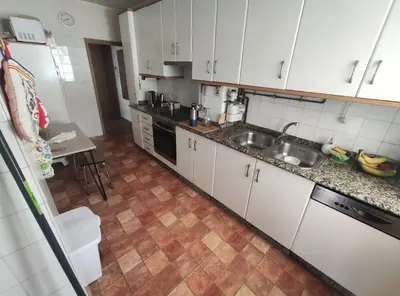 a small kitchen with white cabinets and a sink at Mira a Parque in Lugo
