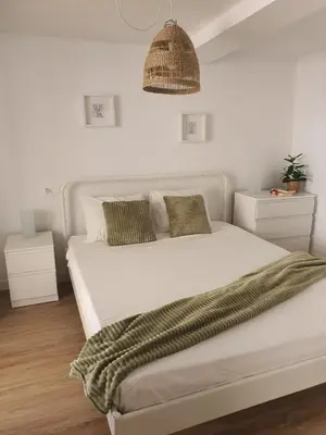 a bedroom with a large white bed with green pillows at Apartamento casco viejo in Ourense