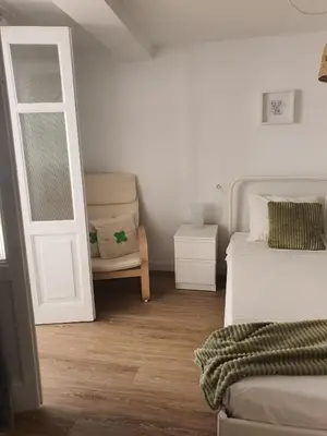 a bedroom with a bed and a door and a chair at Apartamento casco viejo in Ourense
