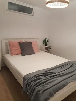 a bedroom with a white bed with pink and grey pillows at Apartamento casco viejo in Ourense