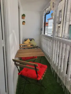 a table and a red chair on a balcony at Apartamento casco viejo in Ourense