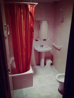 a bathroom with a red shower curtain and a sink at Hostal Monteclaro in Ponferrada