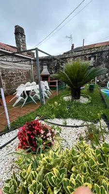 a garden with flowers and a table and chairs at Casa a Voada - Rural con Piscina Privada, Barbacoa y Juegos in Muiños