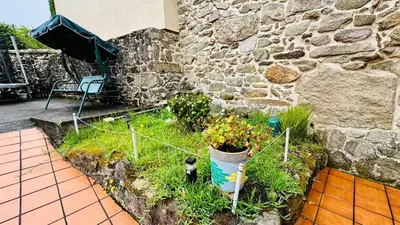 a garden with plants in a stone wall at Casa a Voada - Rural con Piscina Privada, Barbacoa y Juegos in Muiños