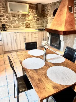 a wooden table with four chairs and a fireplace at Casa a Voada - Rural con Piscina Privada, Barbacoa y Juegos in Muiños