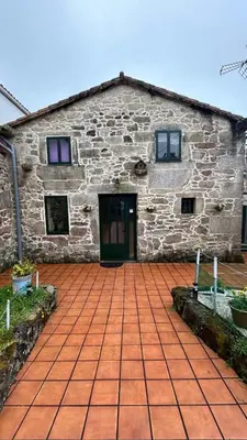 a stone building with a door and a brick patio at Casa a Voada - Rural con Piscina Privada, Barbacoa y Juegos in Muiños