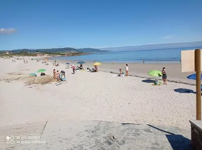 a group of people on a beach with umbrellas at EnFOZ PLAYA PISCINA Y PARKING in Foz