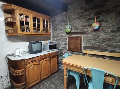 a kitchen with a table with a microwave and a tv at Casa Moucheiro in Lugo