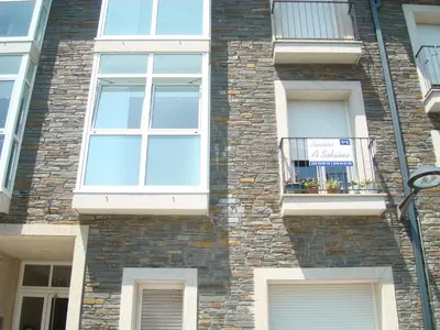 a brick building with windows and a sign on it at Pensión A Solaina in O Pedrouzo