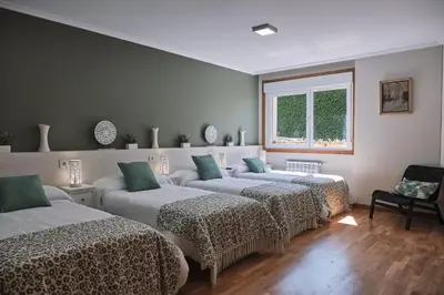 a room with three beds and a window at Pensión A Solaina in O Pedrouzo