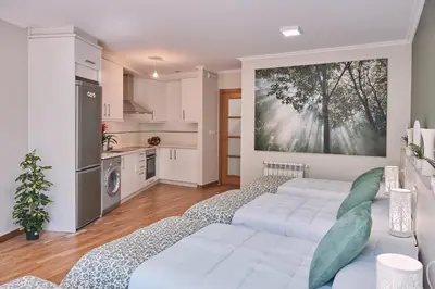 a living room with two beds and a kitchen at Pensión A Solaina in O Pedrouzo