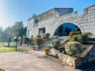 a house with a stone wall and some plants at O Souto de Monteasnal in Ourense