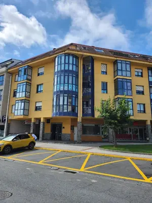 a yellow building with a car parked in a parking lot at Ciudad De Sada in Sada