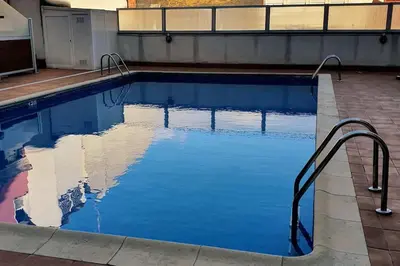 a swimming pool with blue water in a building at Apartamento en el centro de FOZ in Foz