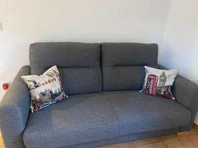 a gray couch with two pillows on it at Apartamento Sant-Yago in Santiago de Compostela