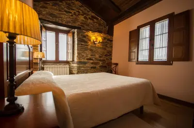 a bedroom with a bed and a brick wall at Apartamentos El Sualleiro in Santa Eulalia de Oscos