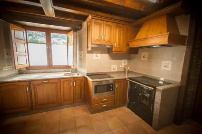 a kitchen with wooden cabinets and a stove top oven at Apartamentos El Sualleiro in Santa Eulalia de Oscos