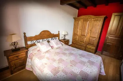 a bedroom with a large bed and a wooden cabinet at Apartamentos El Sualleiro in Santa Eulalia de Oscos
