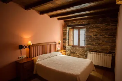 a bedroom with a bed and a stone wall at Apartamentos El Sualleiro in Santa Eulalia de Oscos