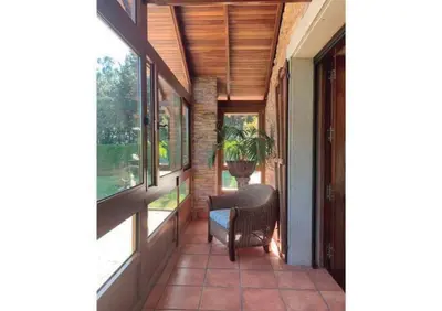 a porch of a house with a chair and windows at Casa Do Rivera in Cospeito