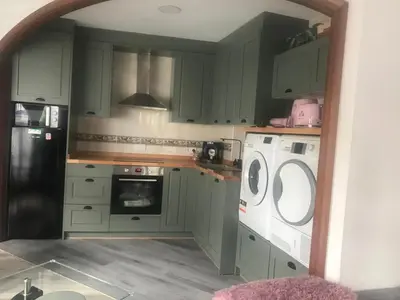 a kitchen with green cabinets and a washer and dryer at Un rincón romano in Caldas de Reis