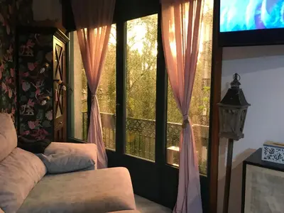 a room with windows with pink curtains and a television at Un rincón romano in Caldas de Reis