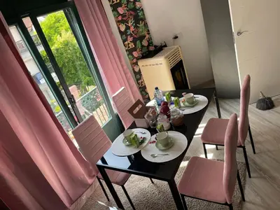 a dining room table with pink chairs and a window at Un rincón romano in Caldas de Reis