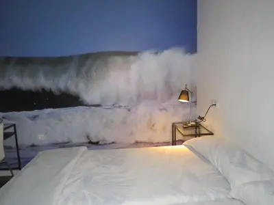 a bedroom with a bed and a large wave on the wall at Refugio O Castro in Barreiros