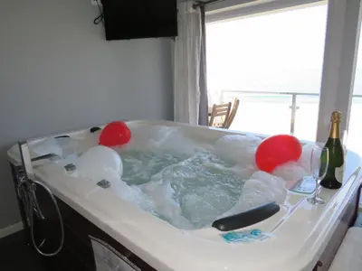 a bath tub with a bottle of wine and balloons in it at Refugio O Castro in Barreiros