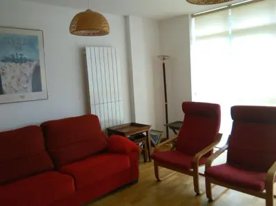a living room with a red couch and two chairs at El apartamento de Ana y Mariano in Foz