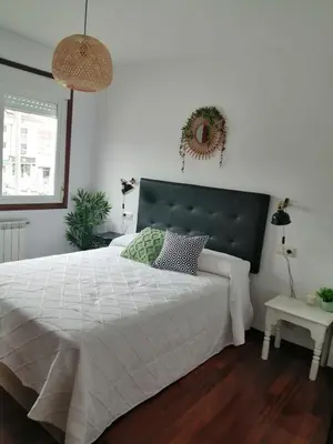 a bedroom with a large white bed with a black headboard at Alojamiento Santa Maria Bertamirans II in Ortoño