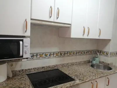 a kitchen with white cabinets and a sink and a microwave at Alojamiento Santa Maria Bertamirans II in Ortoño