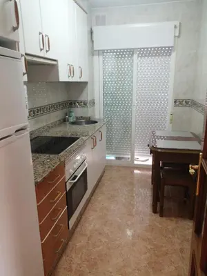 a kitchen with white cabinets and a table and a sink at Alojamiento Santa Maria Bertamirans II in Ortoño