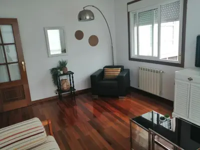 a living room with a black chair and wooden floors at Alojamiento Santa Maria Bertamirans II in Ortoño