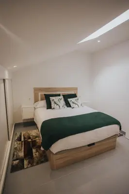 a bedroom with a large bed with green and white sheets at Casas del Pedregal apartamento 3 in A Estrada