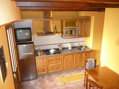a kitchen with a stainless steel refrigerator and a television at Apartamentos Rurales Veredas in Santa Eulalia de Oscos