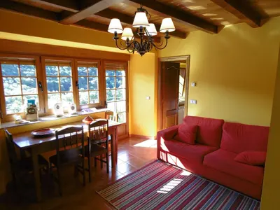 a living room with a red couch and a table at Apartamentos Rurales Veredas in Santa Eulalia de Oscos