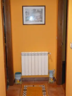 a room with an orange wall with a radiator at Apartamentos Rurales Veredas in Santa Eulalia de Oscos