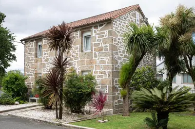 a stone house with palm trees in front of it at Casa San Martiño - Teo in Rua De Francos
