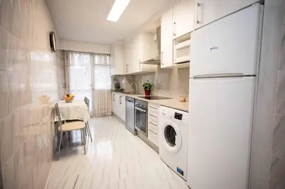 a kitchen with a white refrigerator and a table at Piso Milà in Ourense