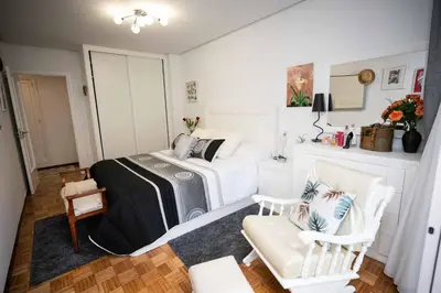 a bedroom with a bed and two white chairs at Piso Milà in Ourense